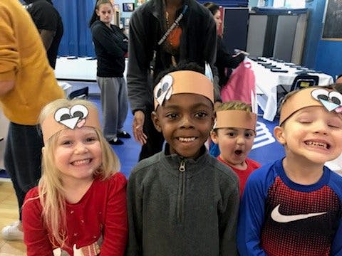 Four children wearing paper headbands with owl faces