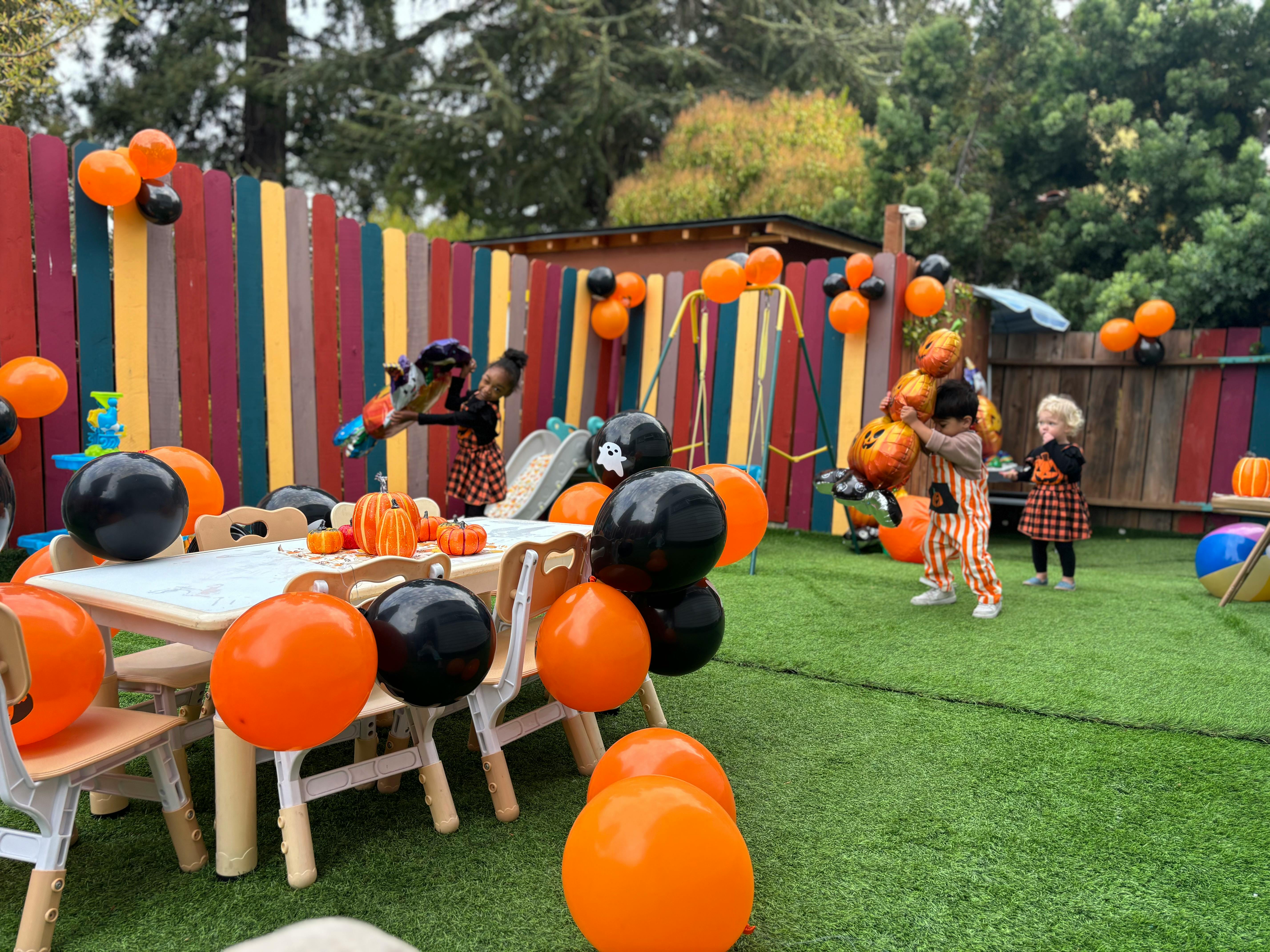 Children playing with balloons in a yard decorated for Halloween