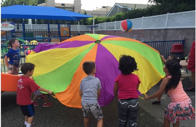 Children playing with a colorful parachute and a ball