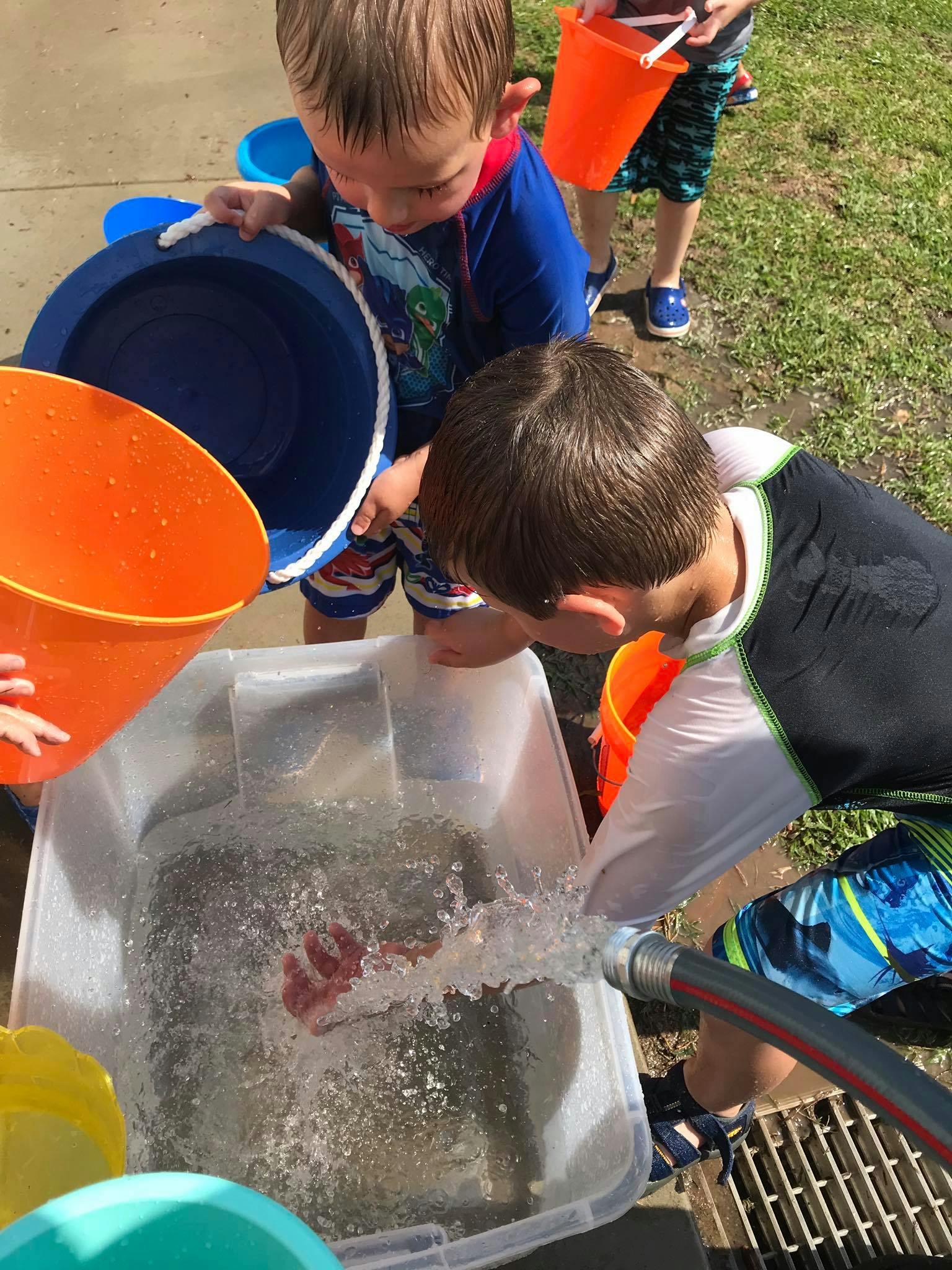 Children playing with water and buckets outdoors