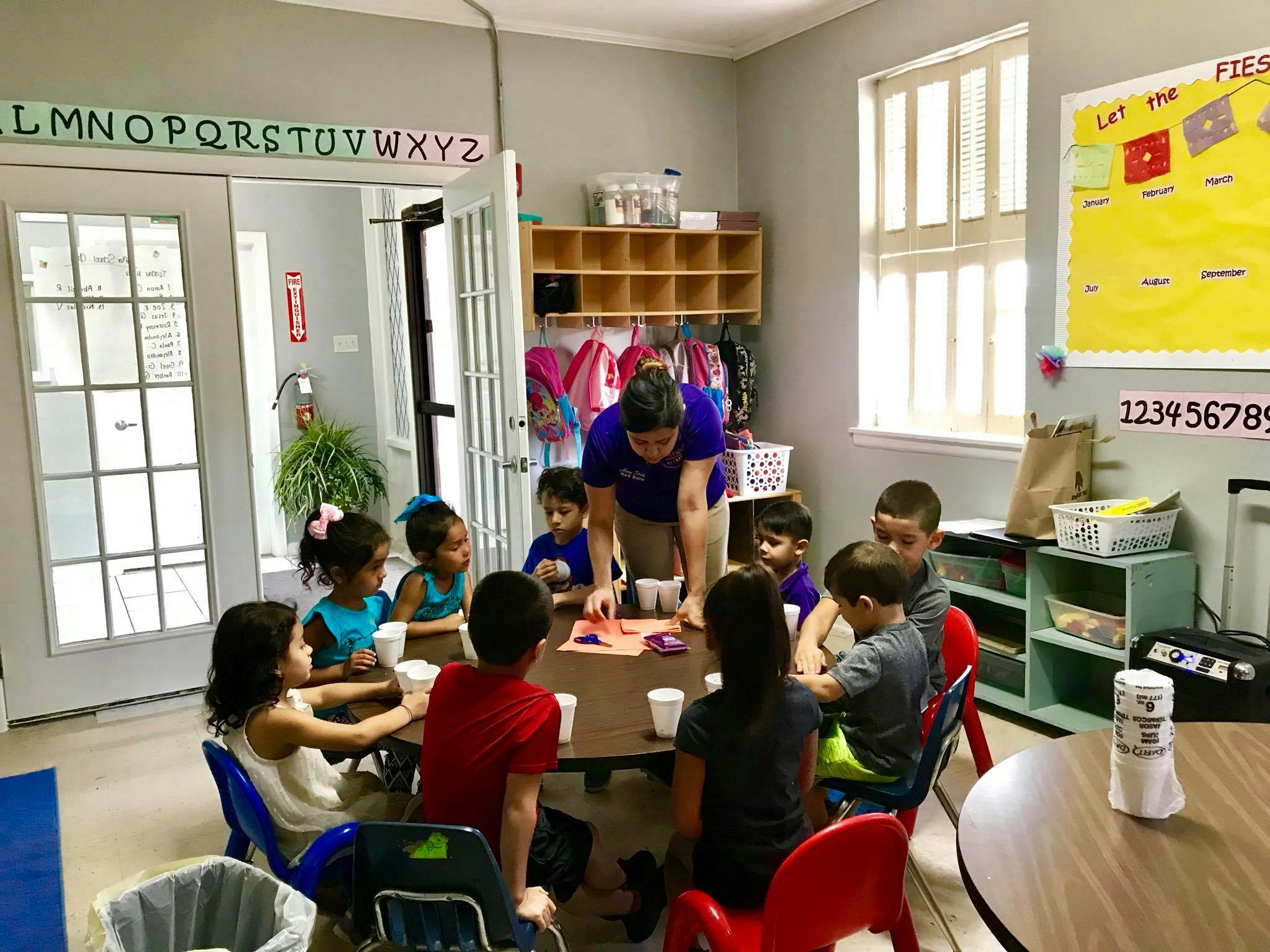 Adult and children gathered around a table in a classroom