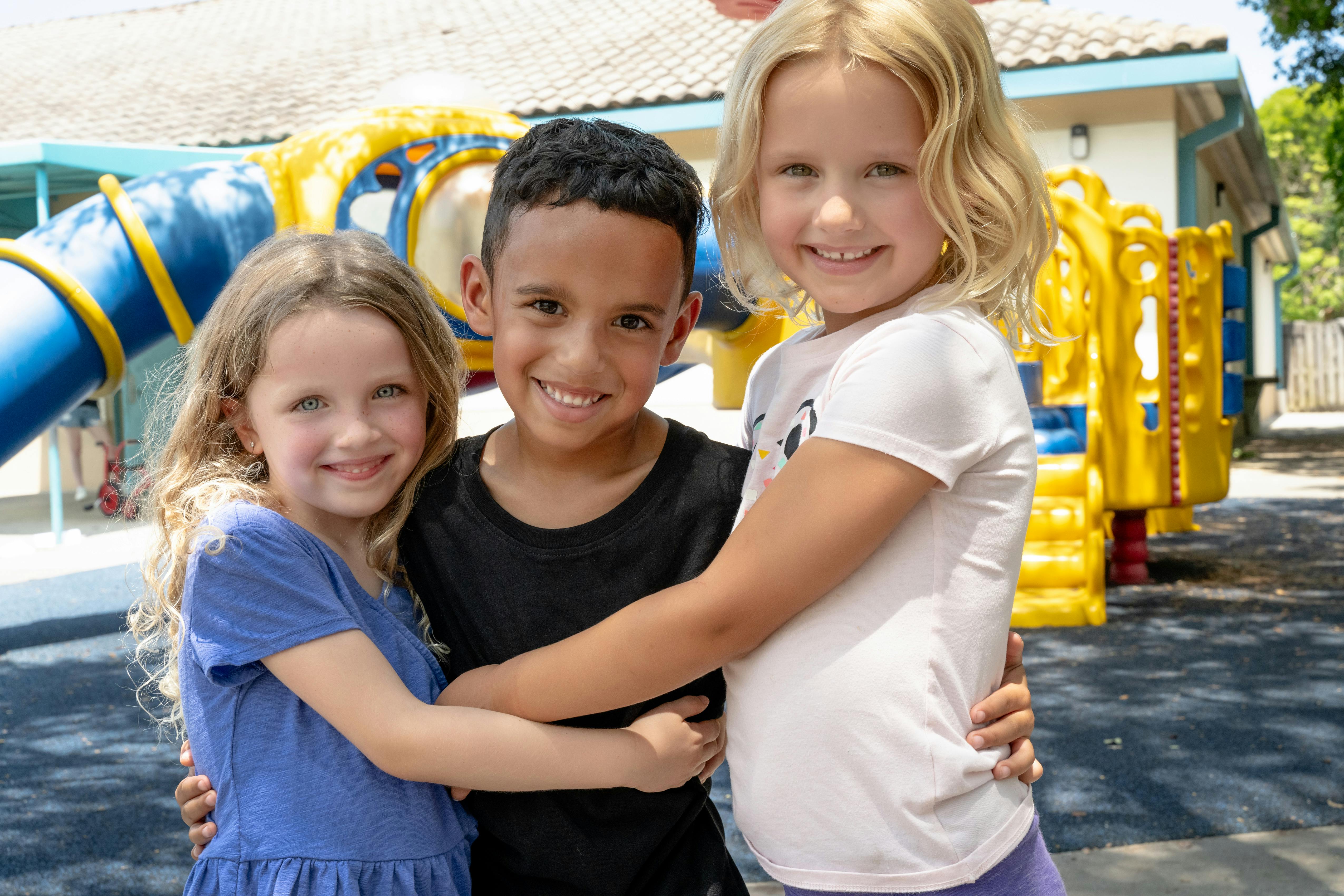 Three children embracing on a playground
