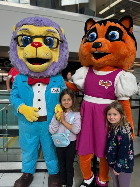 Two children posing with two mascots in costumes