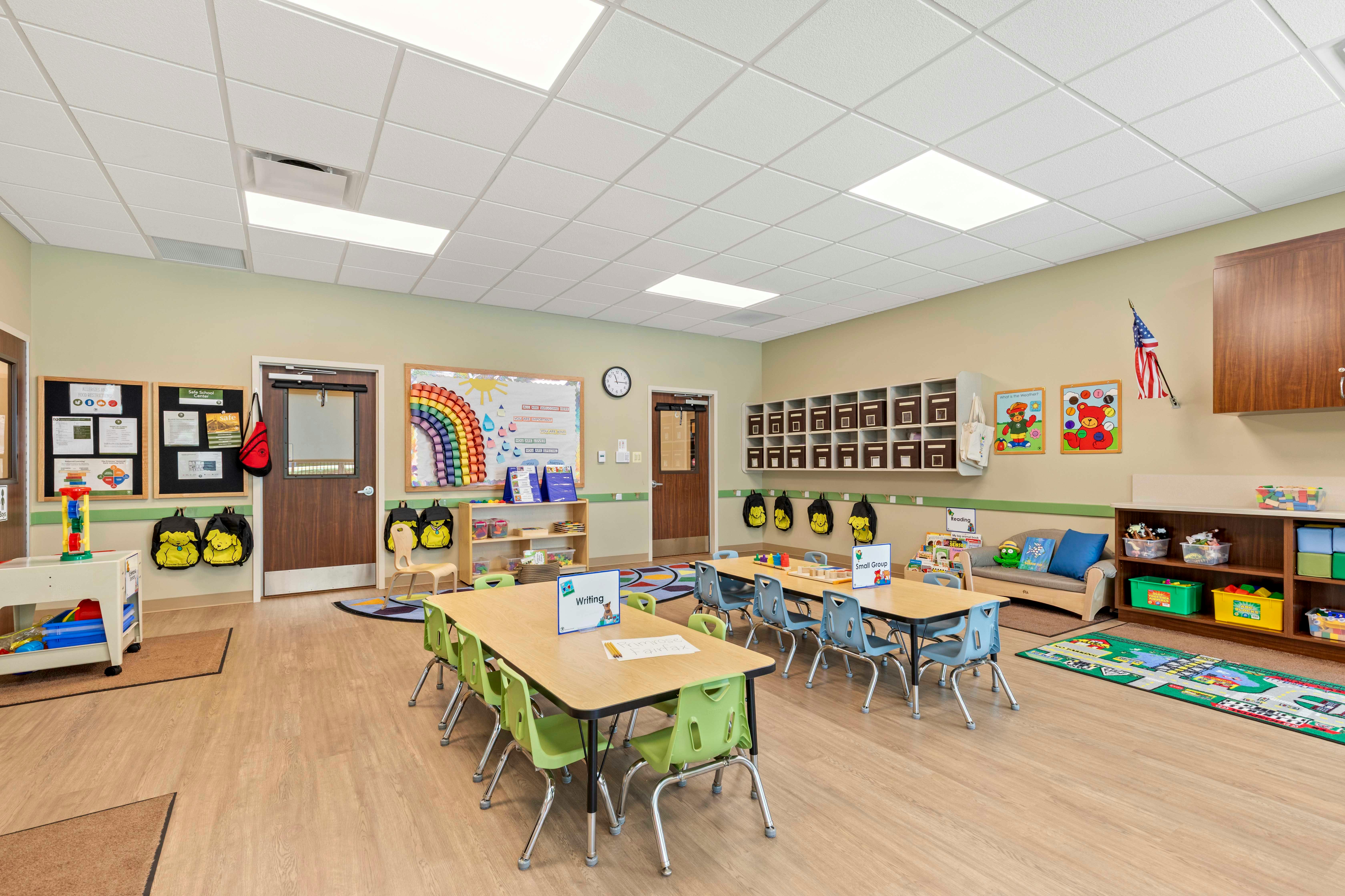 Classroom with small tables and chairs, shelves, and decorations like a rainbow
