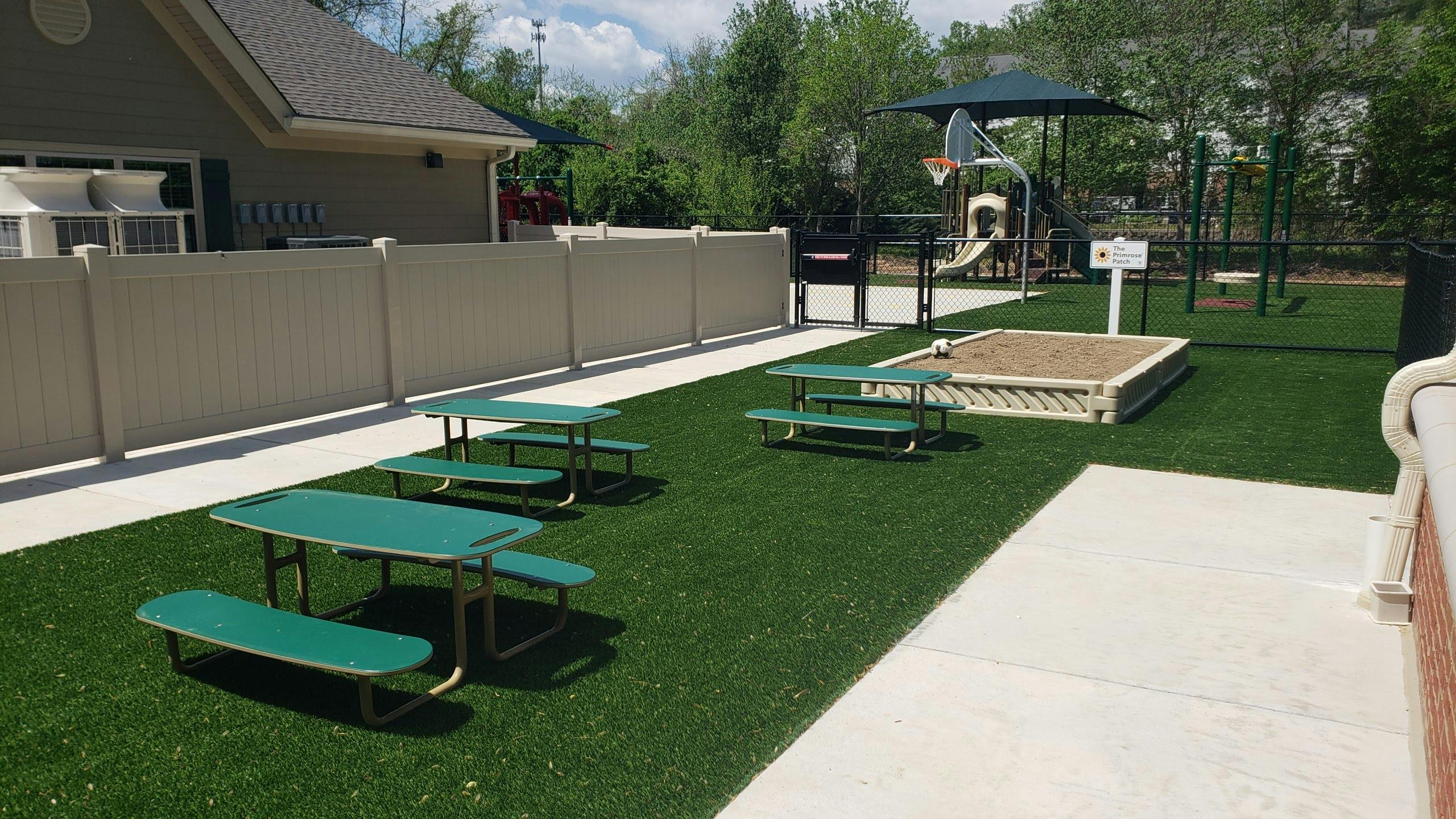 Outdoor playground with picnic tables, sandbox, and play structure