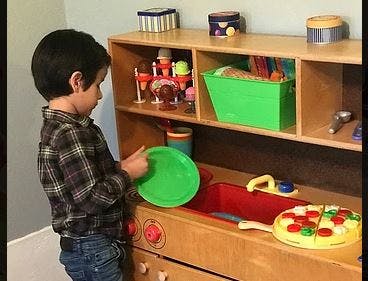 Child playing with a toy kitchen set