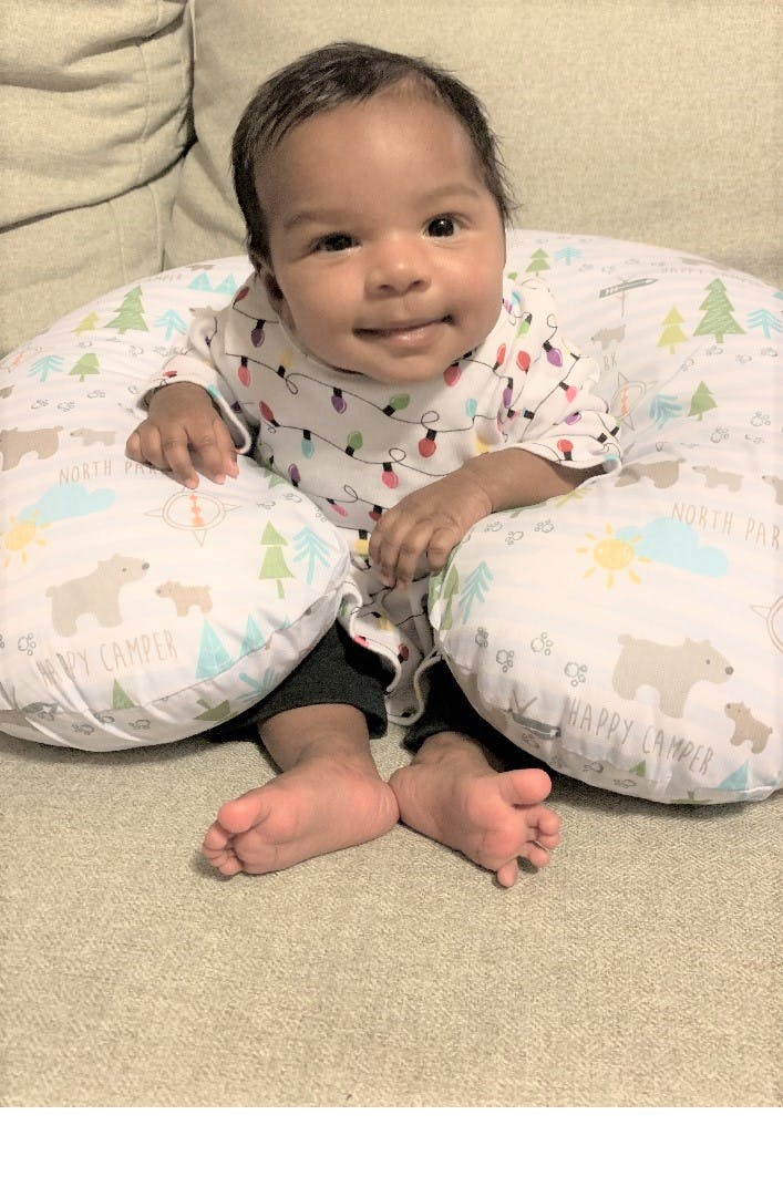 Child sitting in a patterned nursing pillow