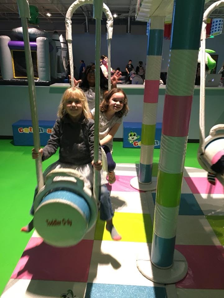 Two children on a swing ride in an indoor play area
