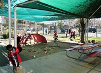 Children playing in a shaded outdoor area with a picnic table