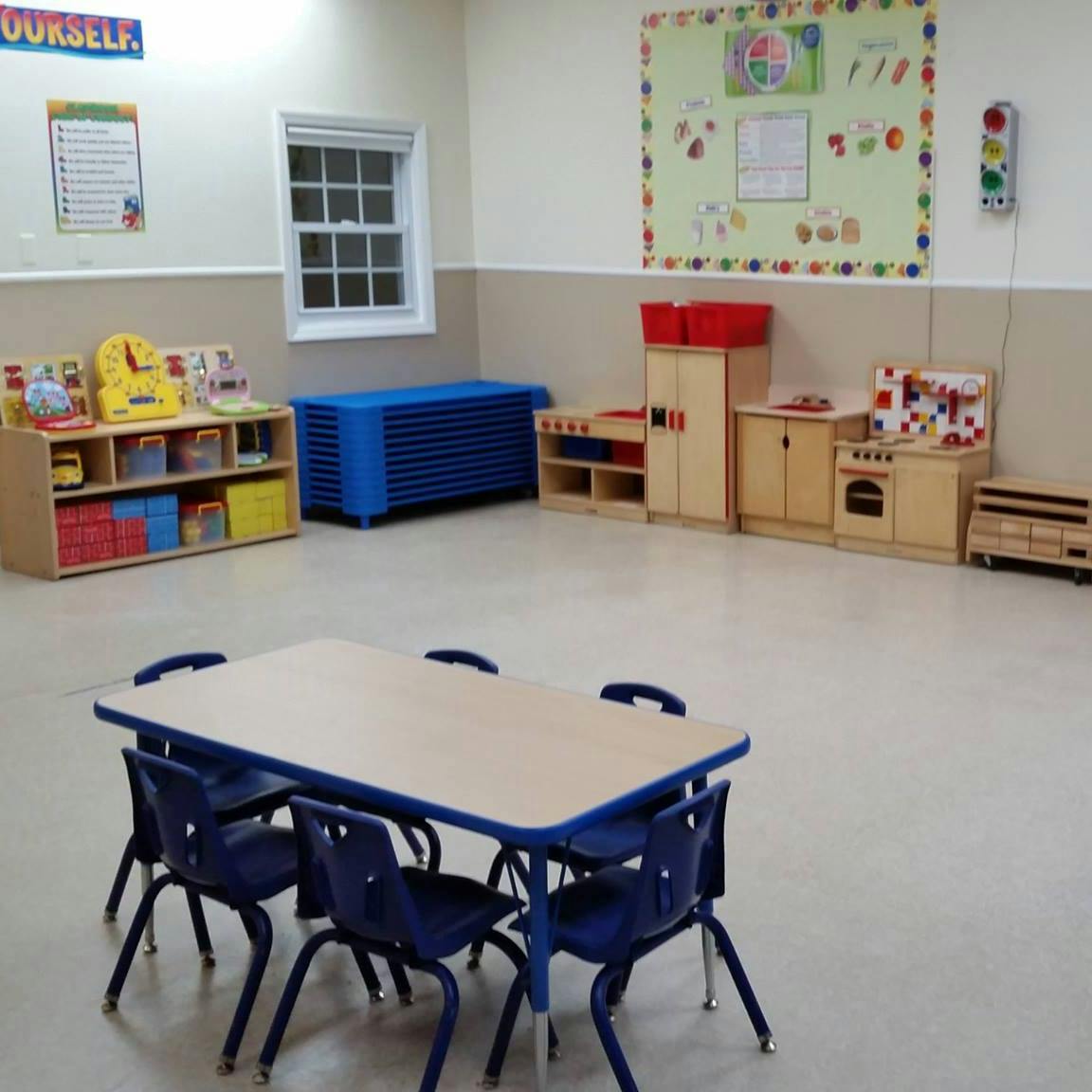 Classroom with small table and chairs, toy kitchen, and storage shelves