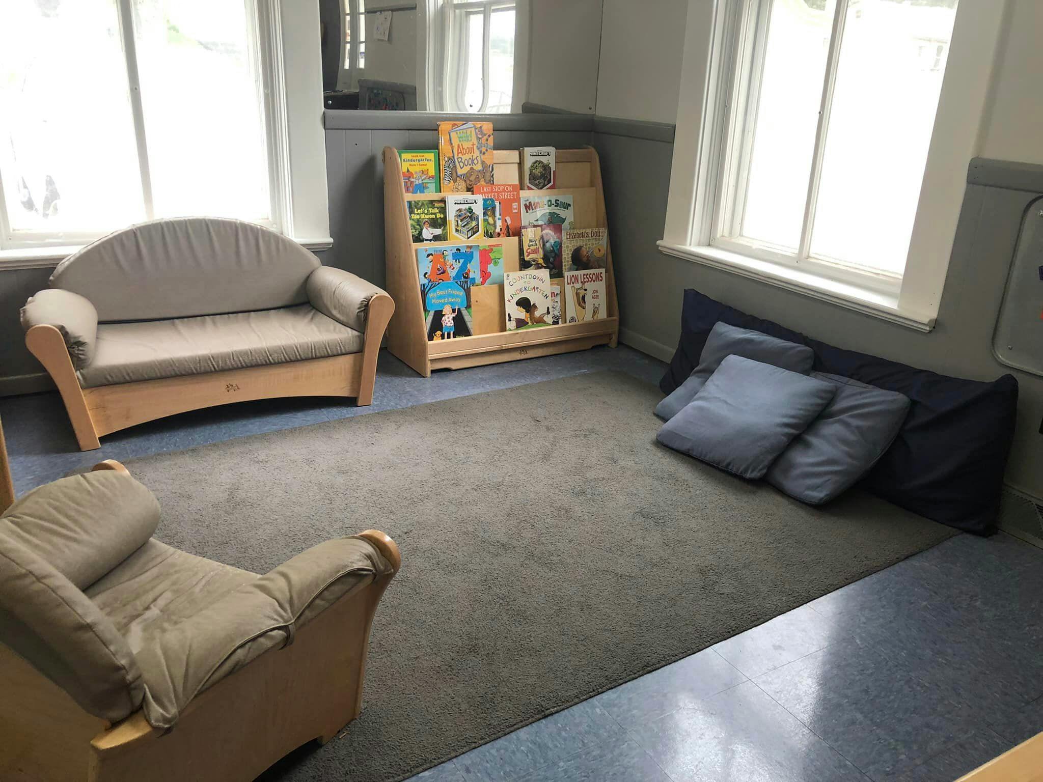 Reading nook with a small couch, armchair, bookshelf, and floor cushions