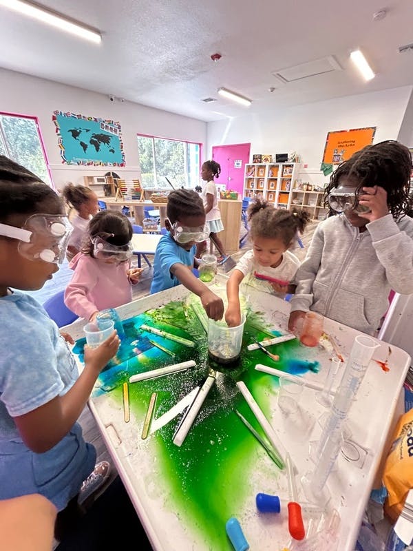 Children wearing safety goggles playing with colorful liquids at a table