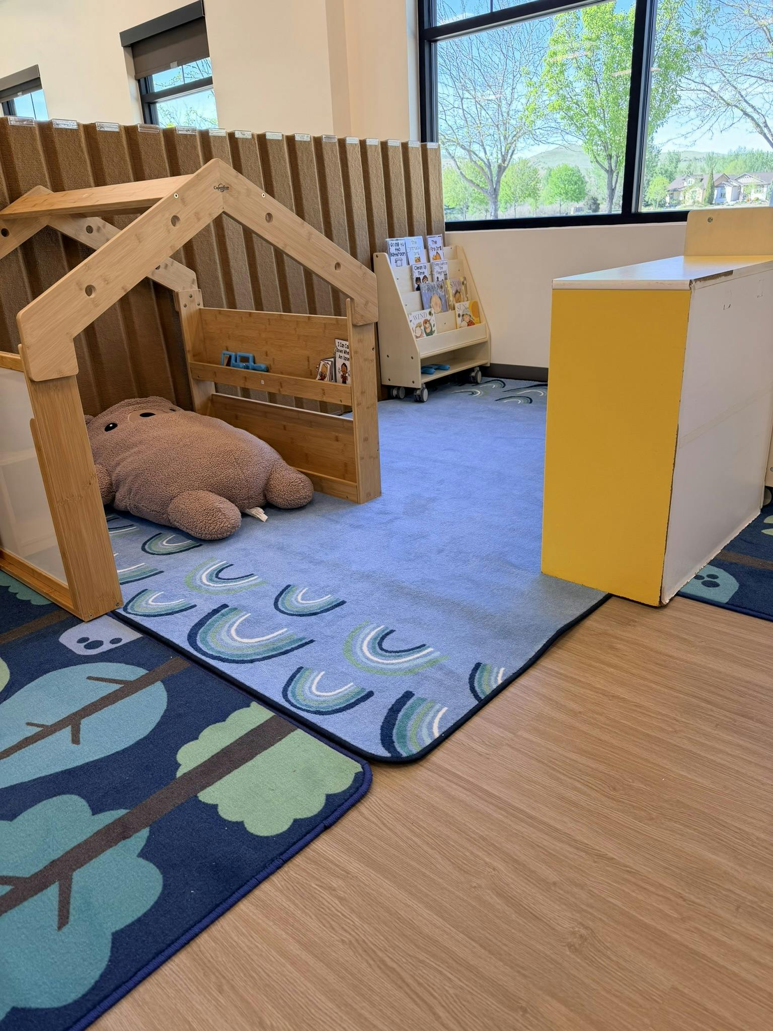 Children's play area with wooden house frame, plush toy, and bookshelves