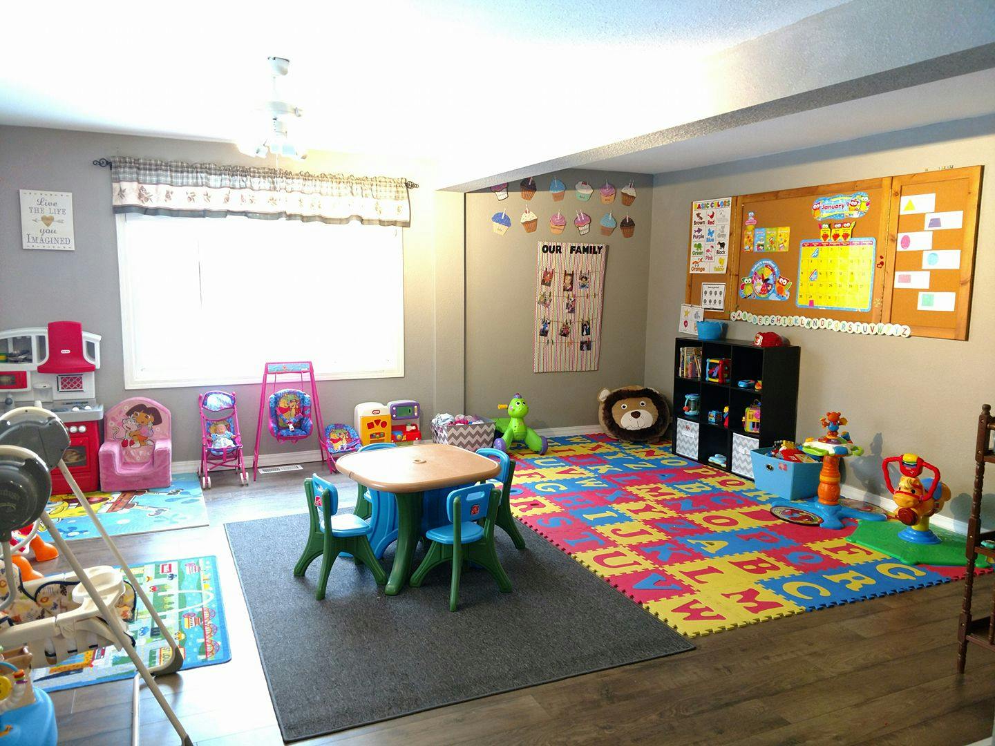 Playroom with a small table and chairs, alphabet mat, and toys