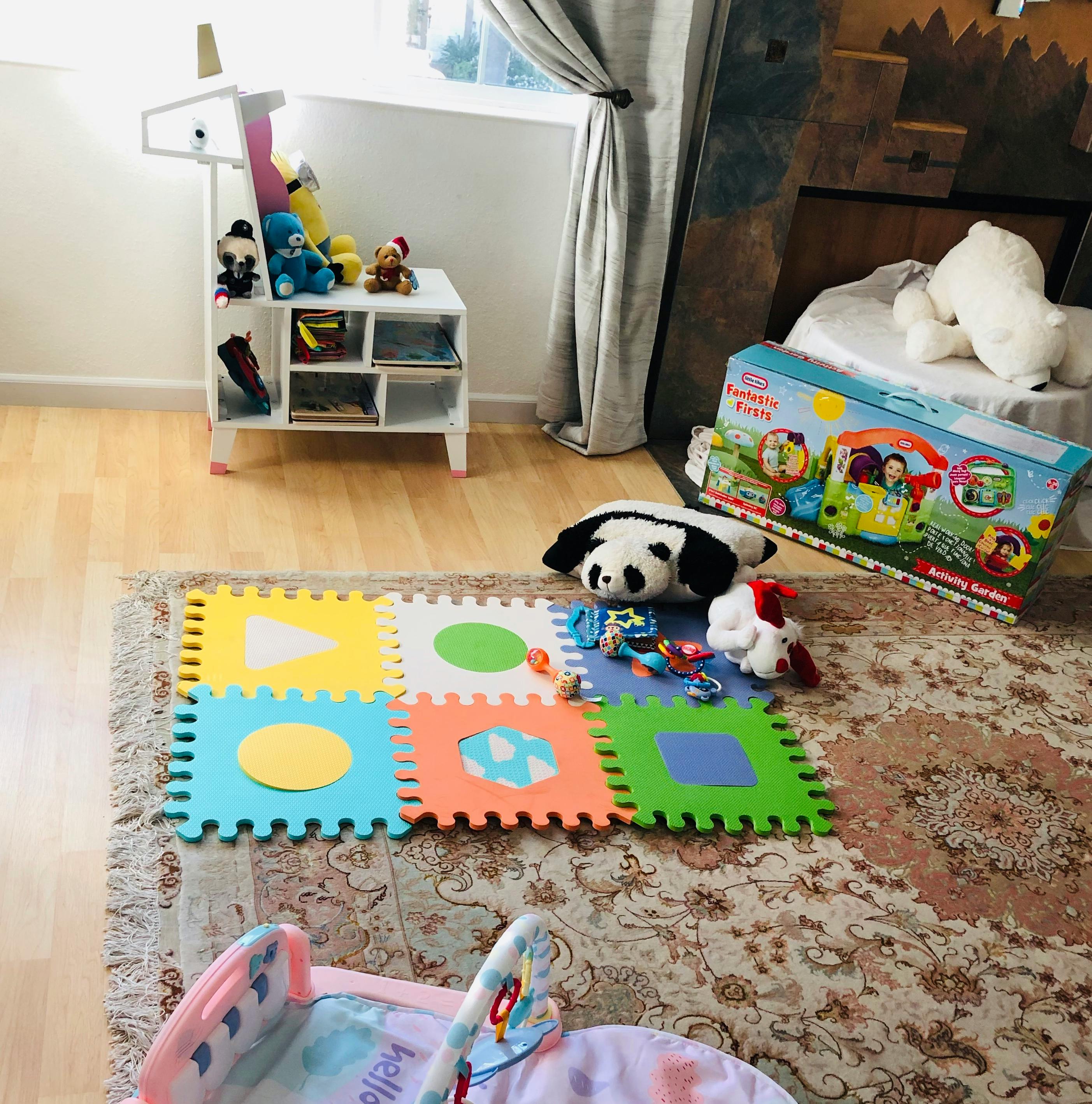 Playroom with colorful foam mat, toys, and baby bouncer