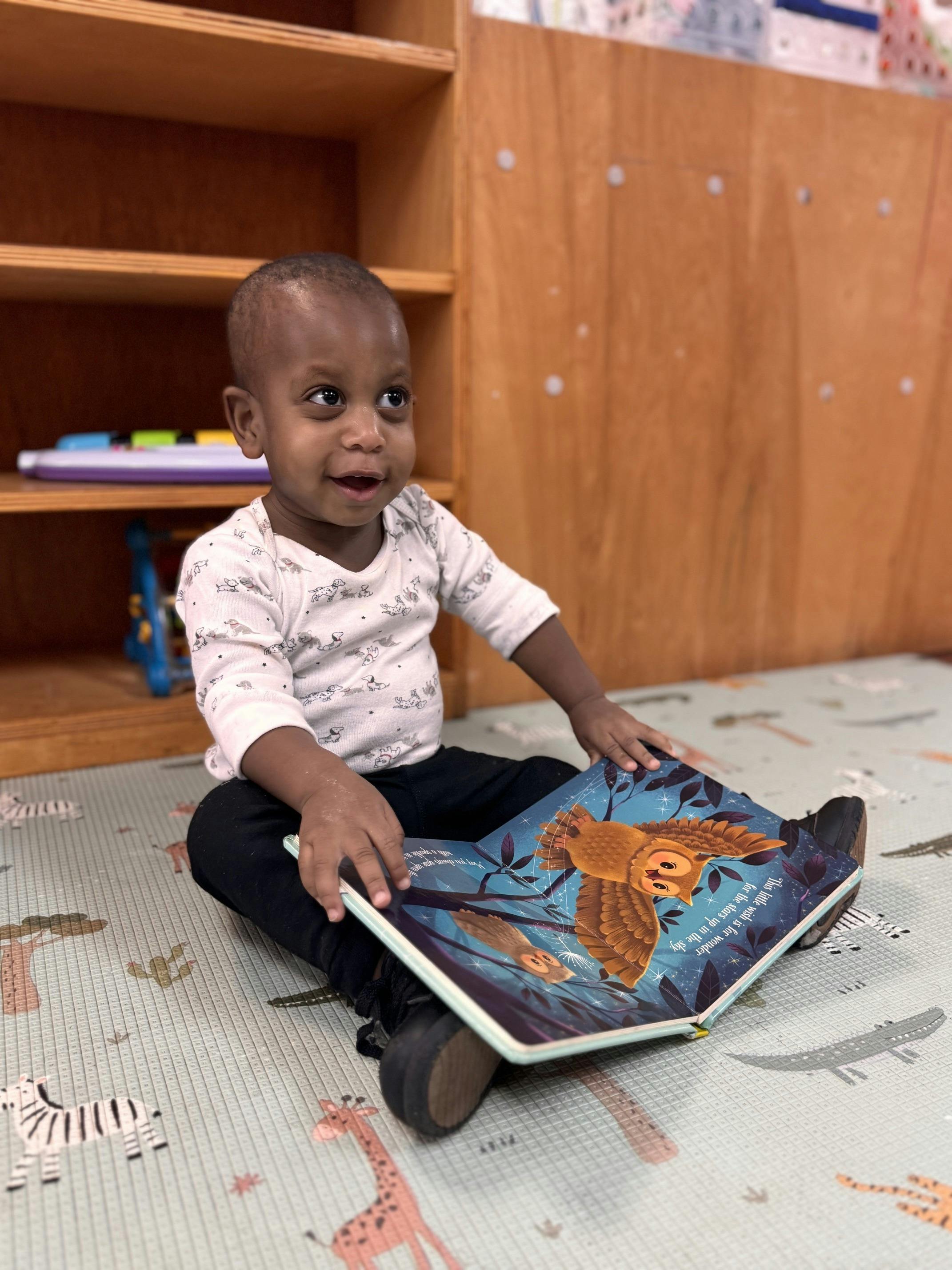 Child sitting on a play mat reading a book