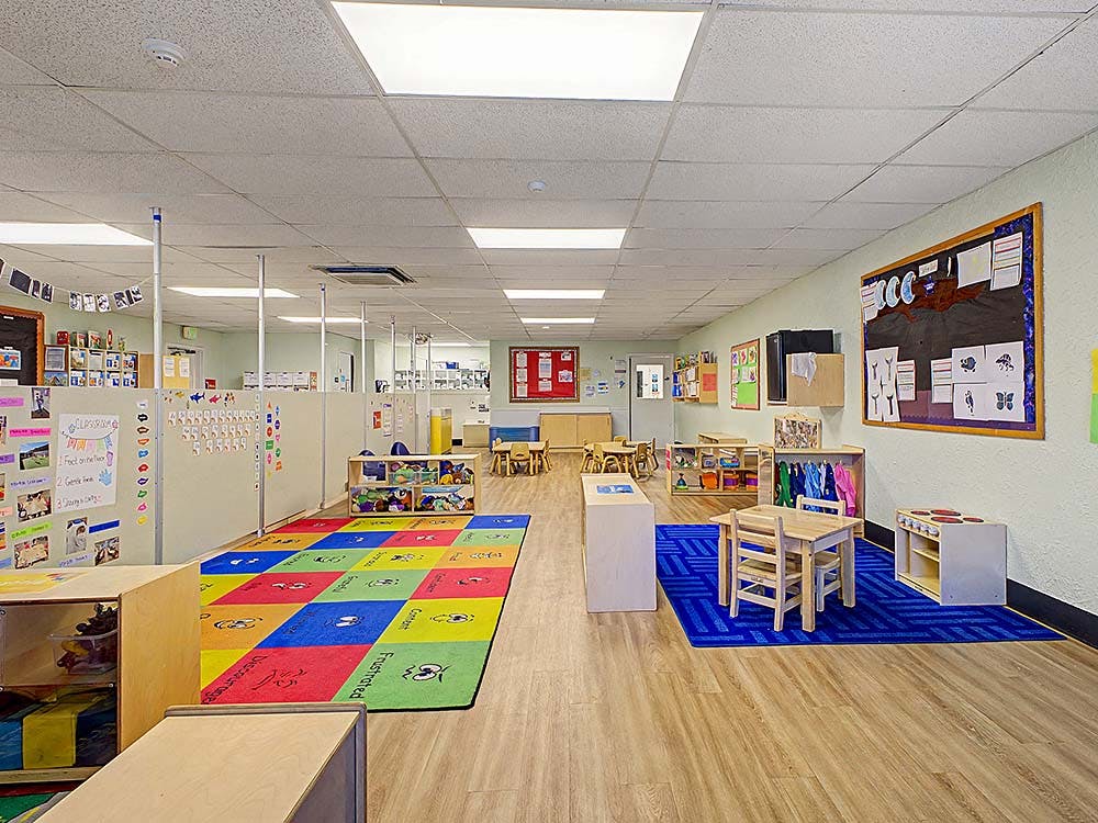 An empty early learning classroom with colorful rugs and small furniture