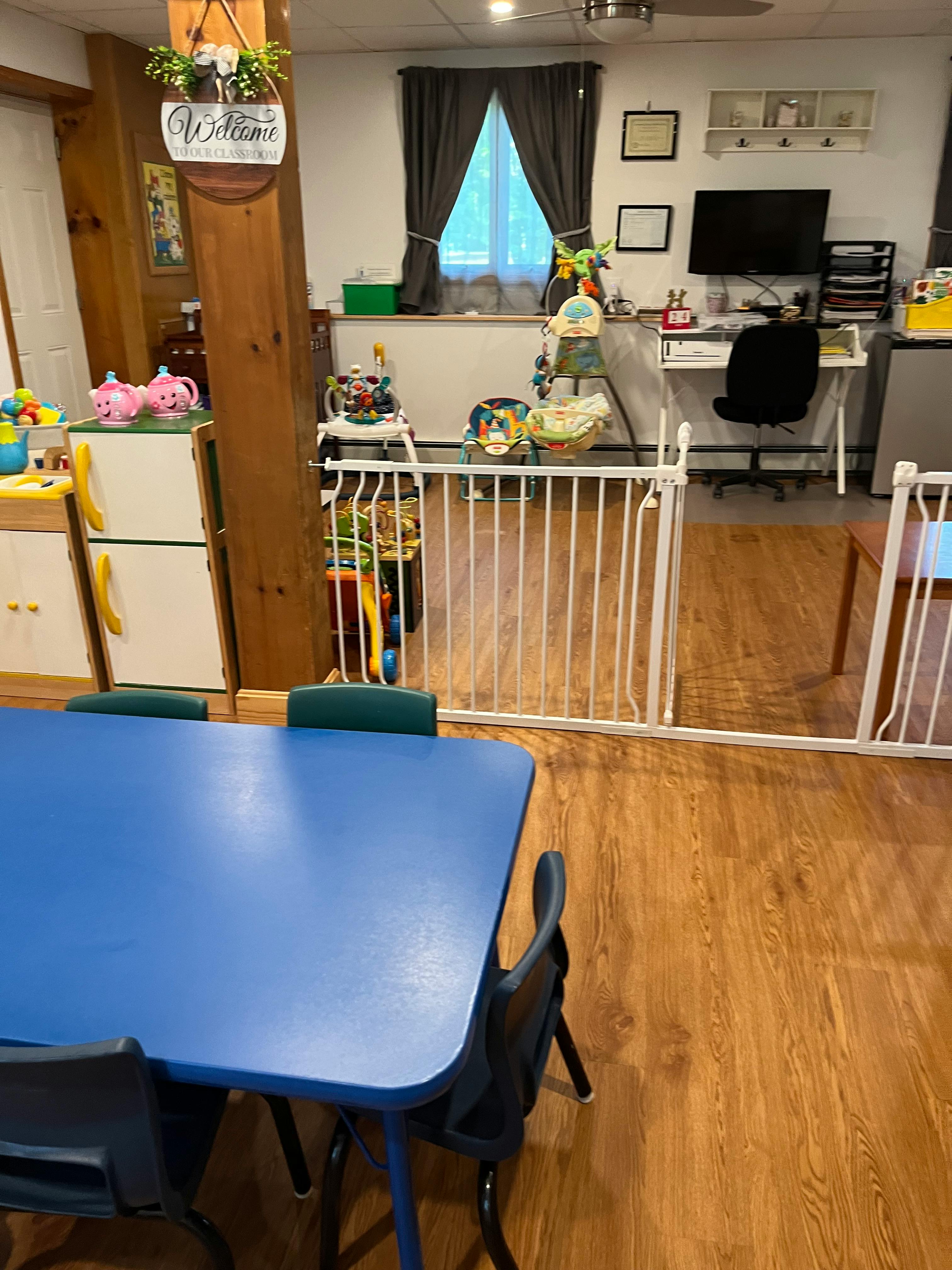 Playroom with a blue table and chairs, baby gate, and toys