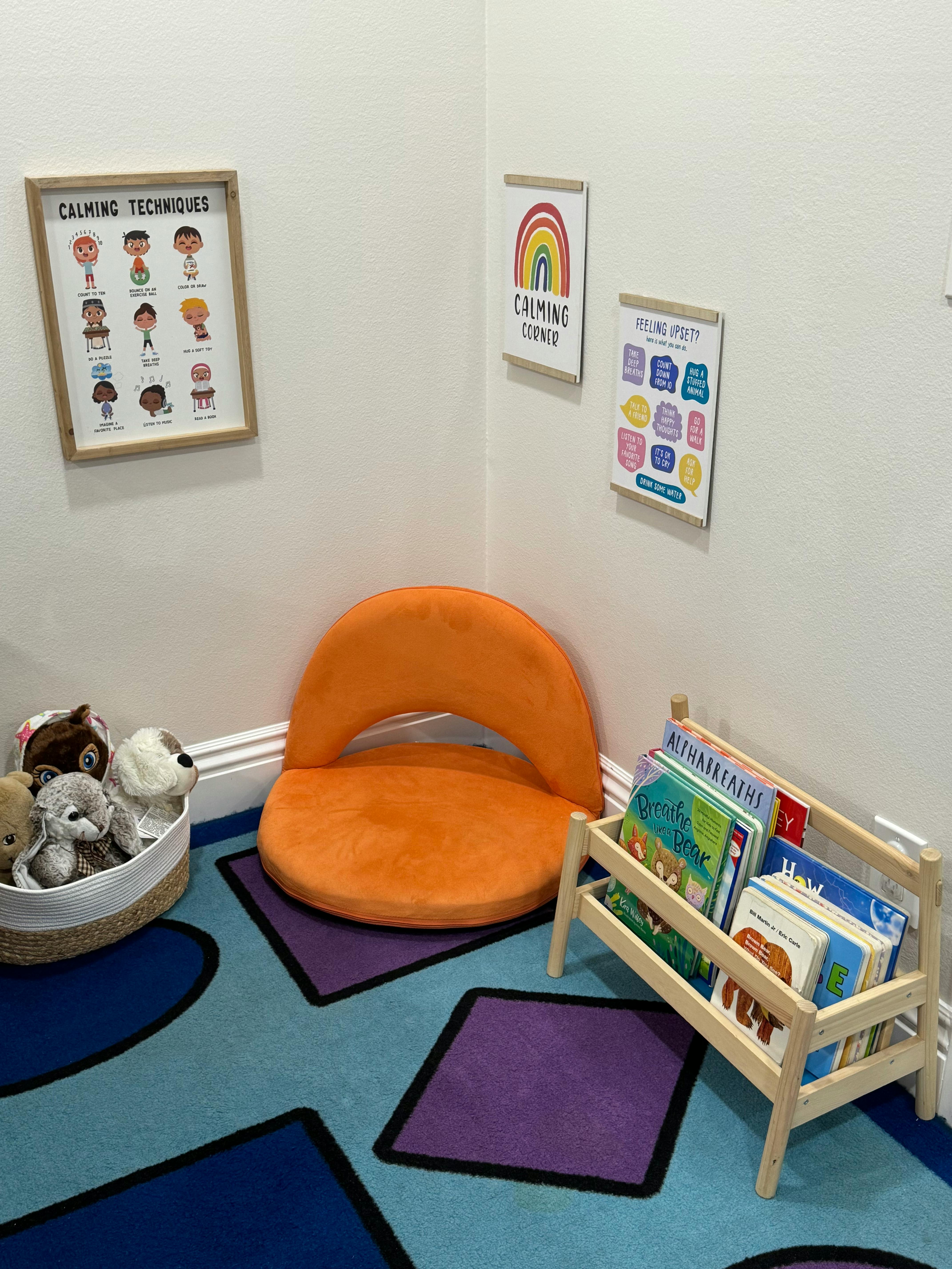 Corner of a room with an orange floor chair, a basket of stuffed animals, and a small bookshelf