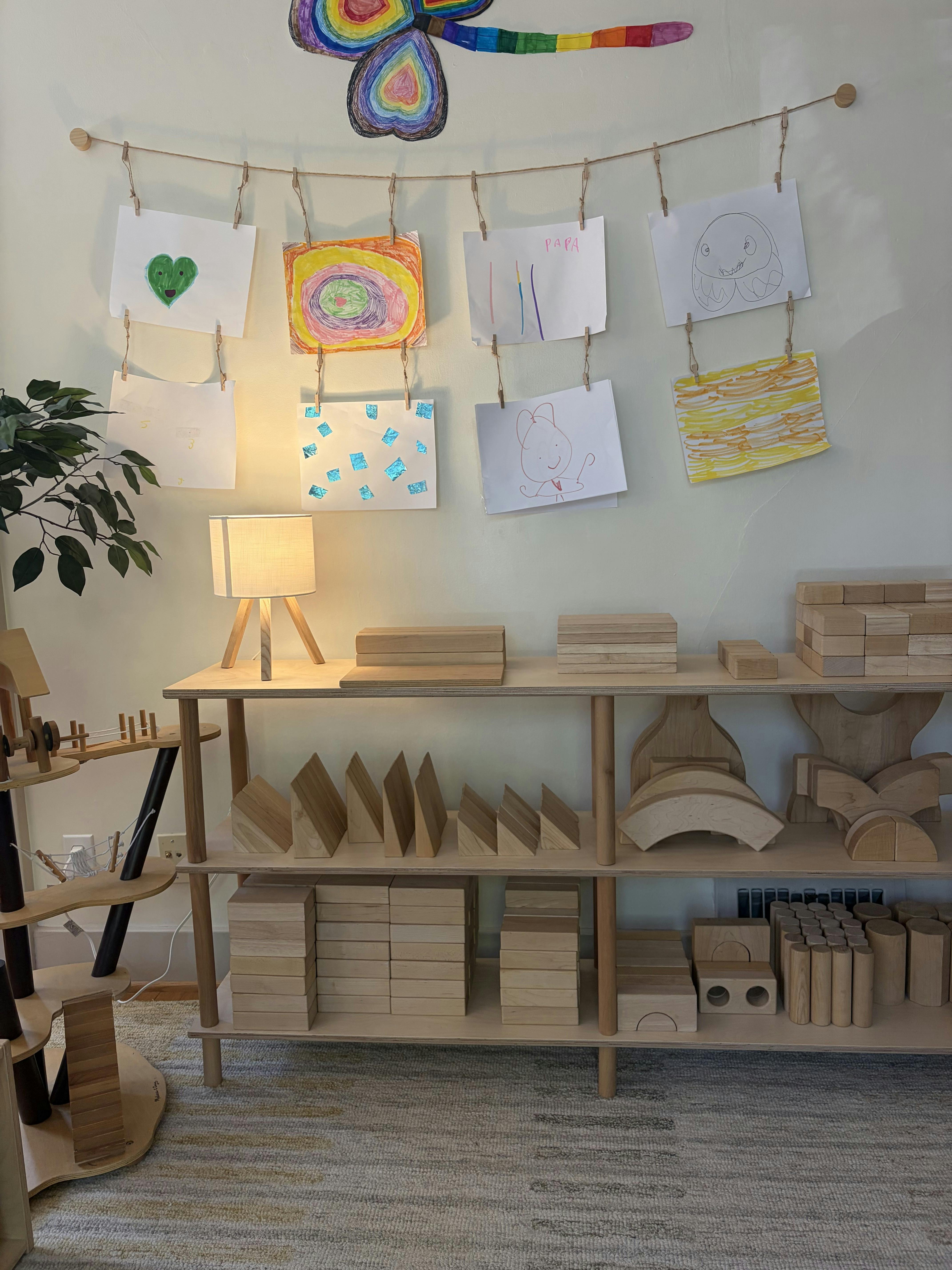 Wooden toy shelf and children drawings hung on wall