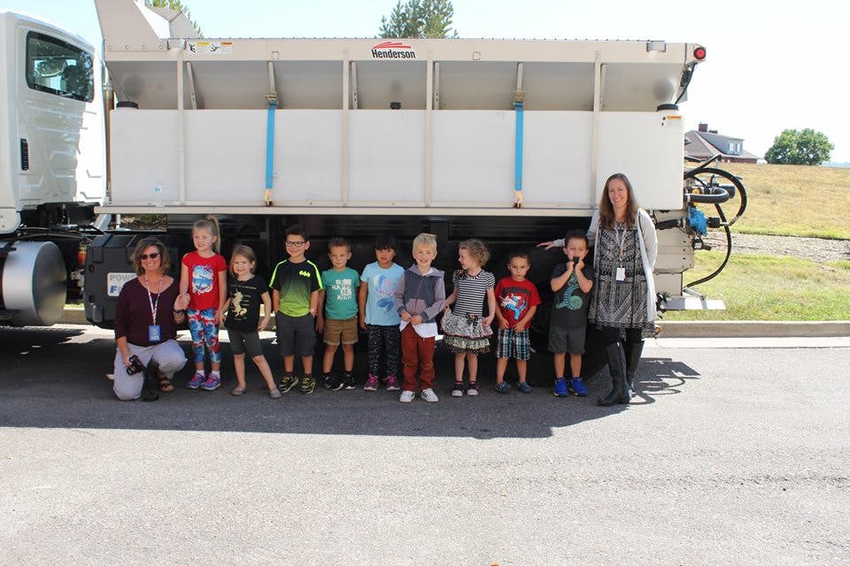 Two people and a group of children standing in front of a large truck