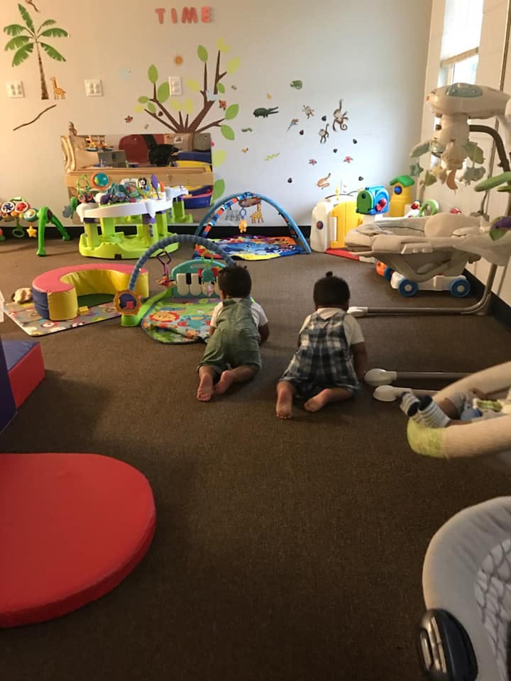 Two children crawling on a carpeted floor in a play area