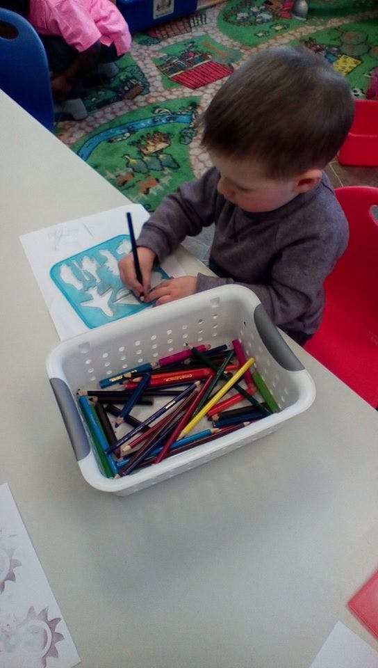 Child coloring a stencil design at a table