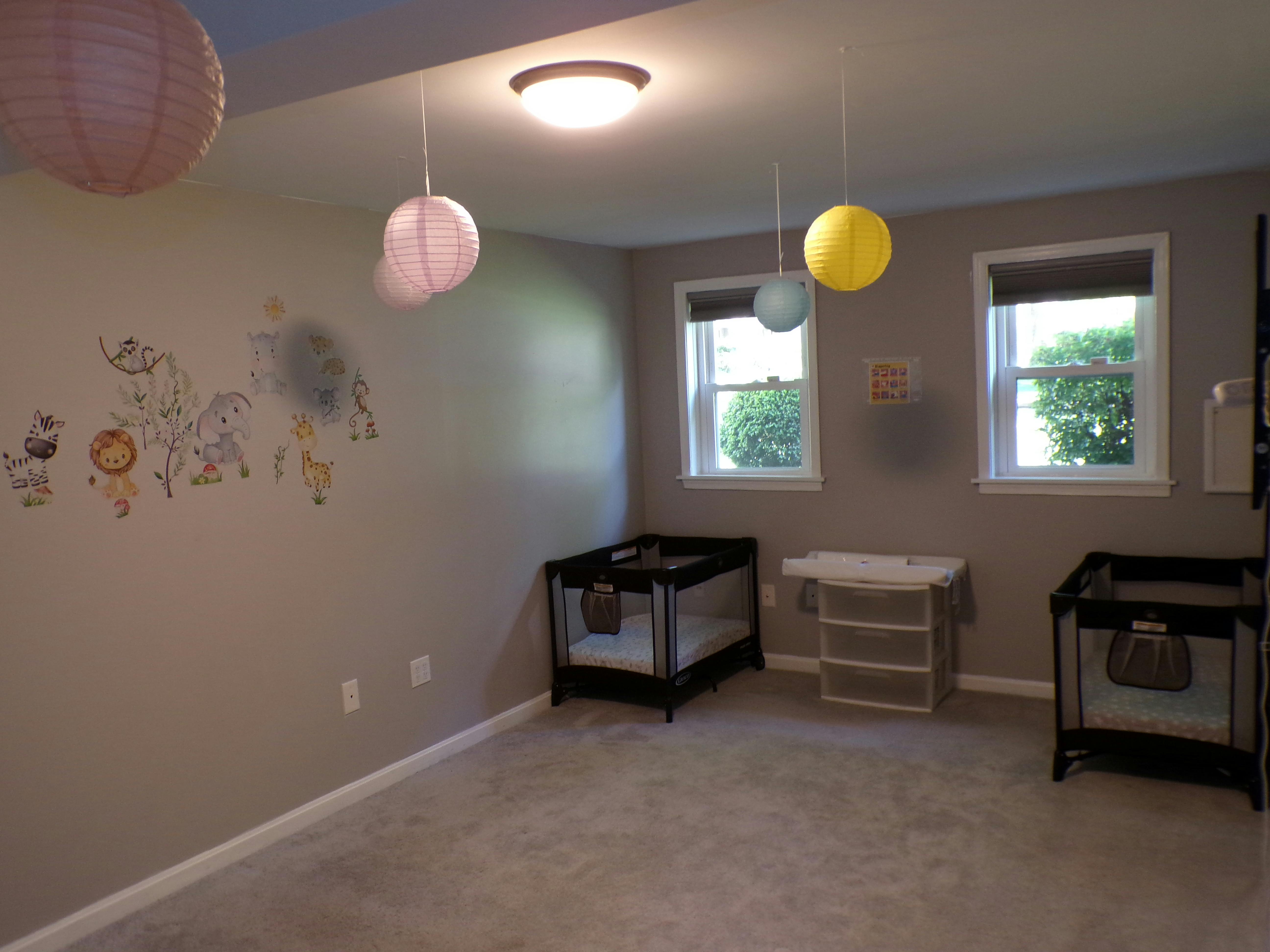 Nursery room with two cribs, a changing table, and wall decals
