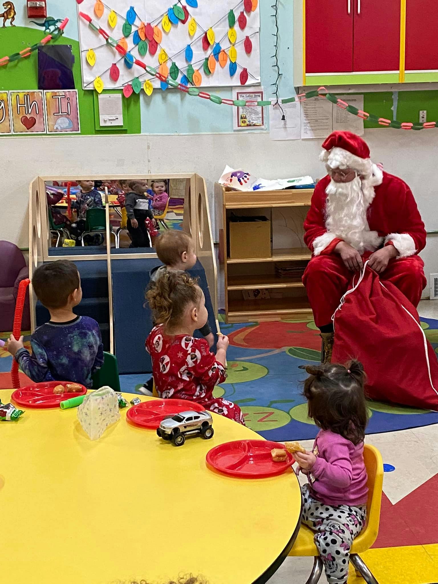 Person dressed as Santa Claus with children in a classroom