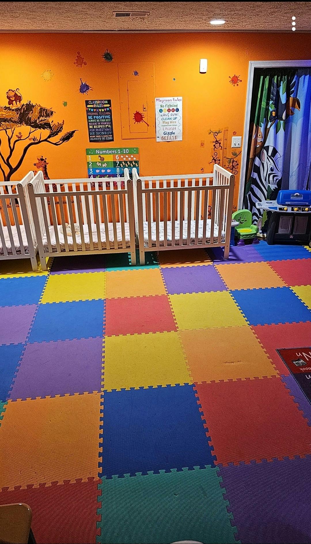 Cribs in a room with a colorful floor and orange wall