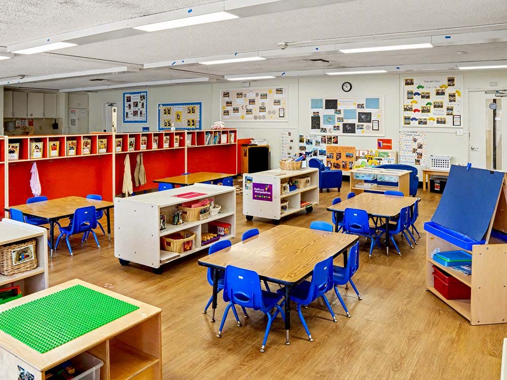 Classroom with small tables, chairs, cubbies, and learning materials