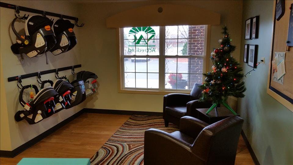 Baby car seats hanging on wall hooks in a room with a decorated Christmas tree