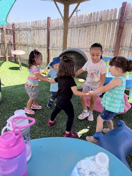 Group of children holding hands in a circle on a playground