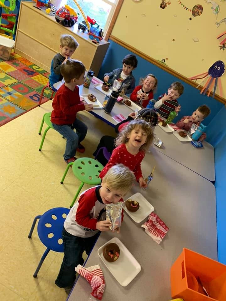 Children sitting at tables eating donuts