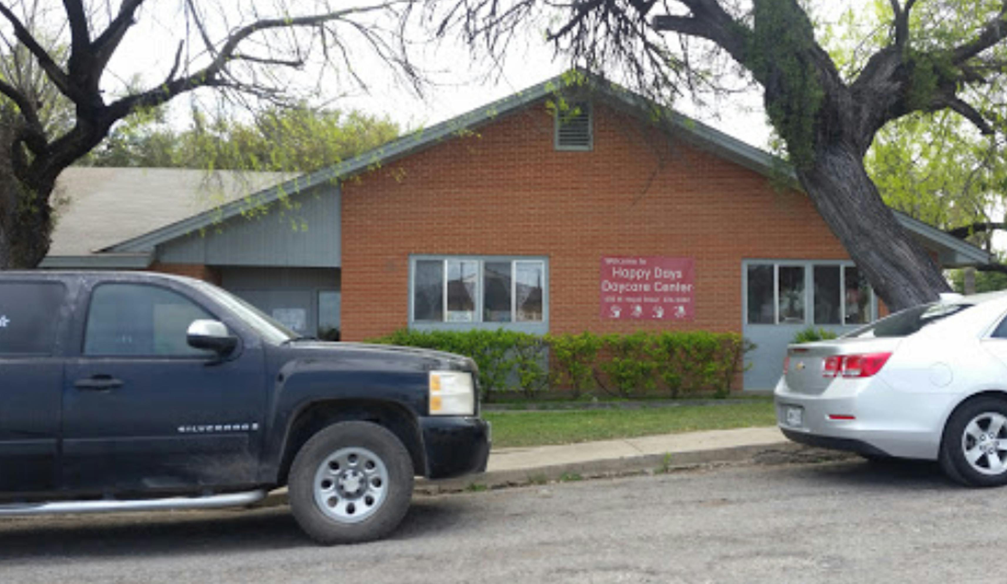 Two cars parked in front of a building with a sign on the wall