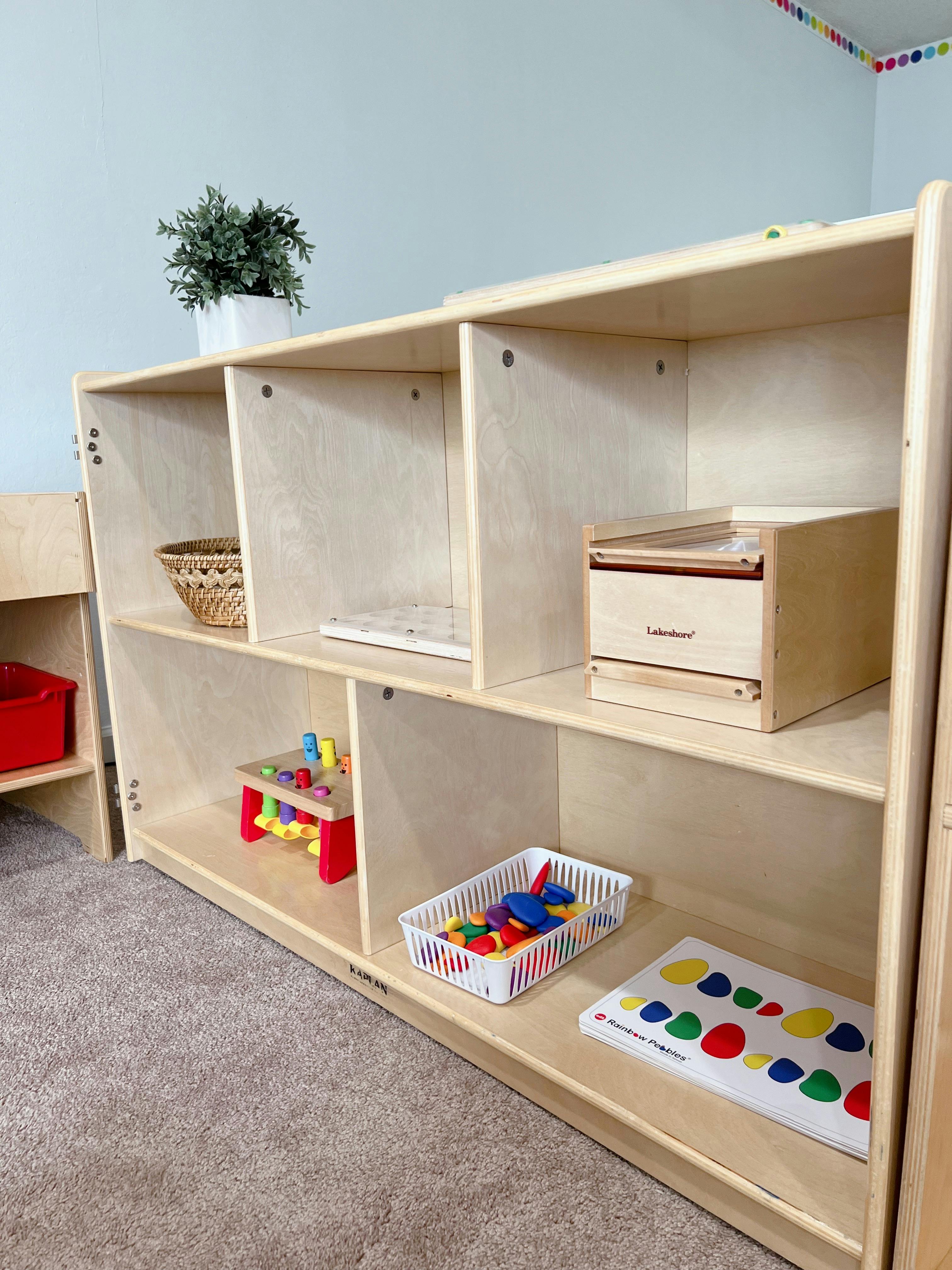 Wooden shelving unit with various toys and a plant in a classroom