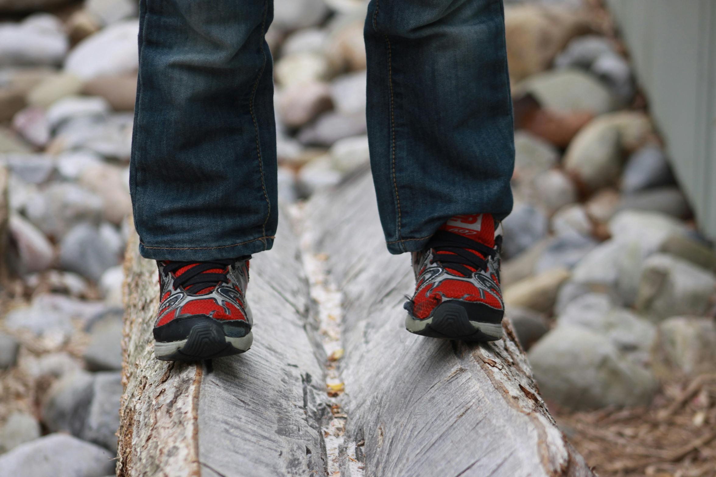 Person in jeans and sneakers balancing on a log