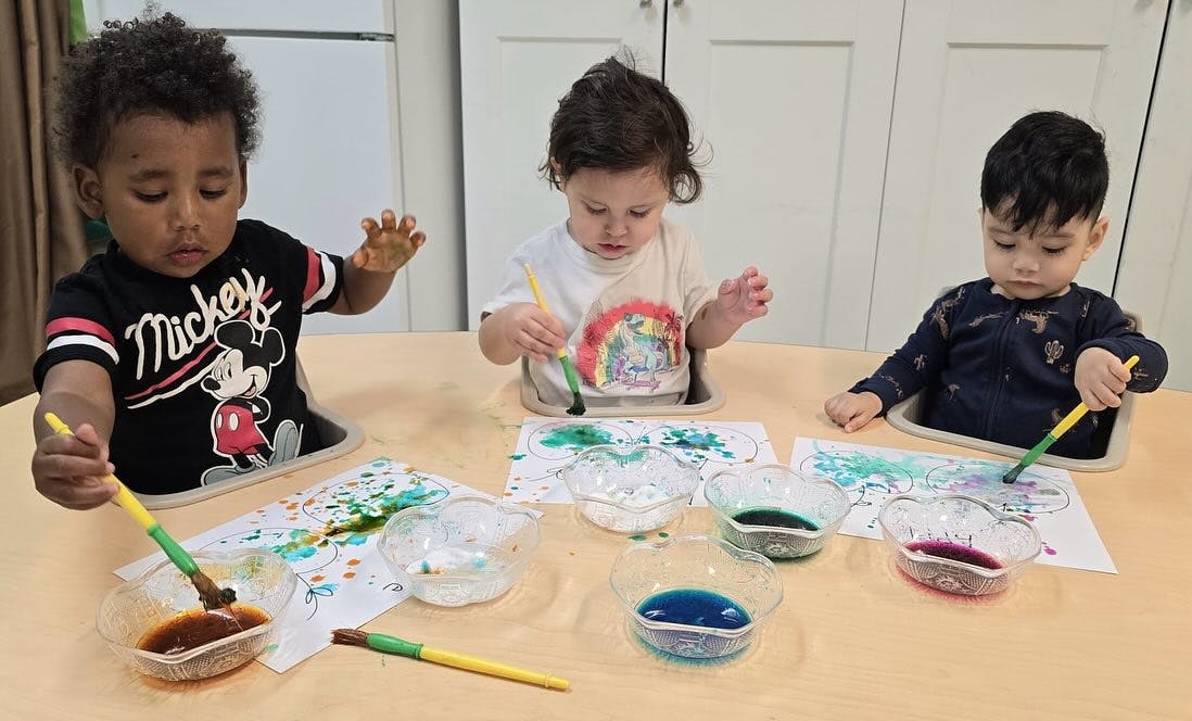 Three children painting at a table