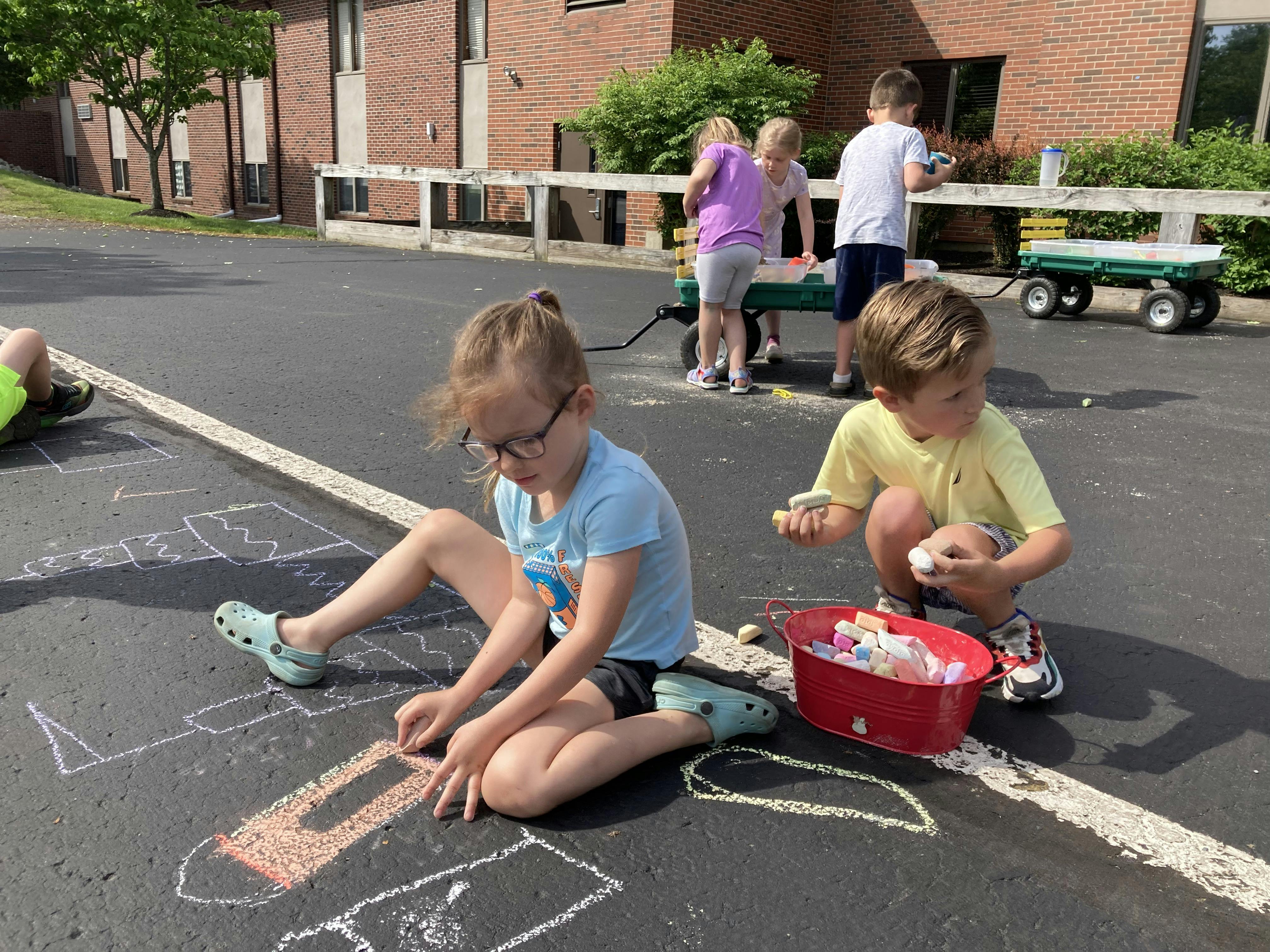 Children drawing with chalk on pavement