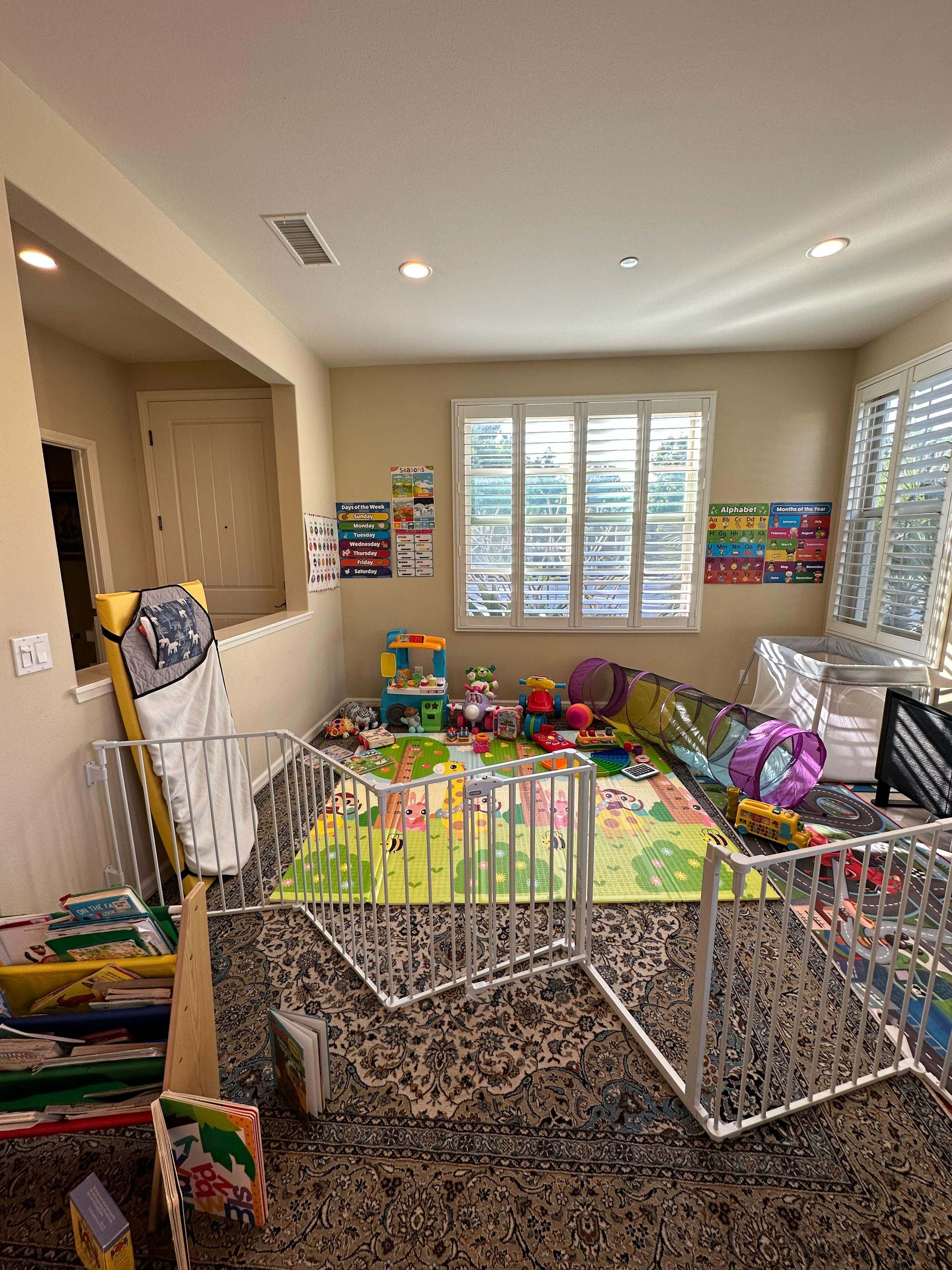Playroom with a playpen, colorful mat, and various toys