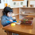 Child at a table with a basket and objects