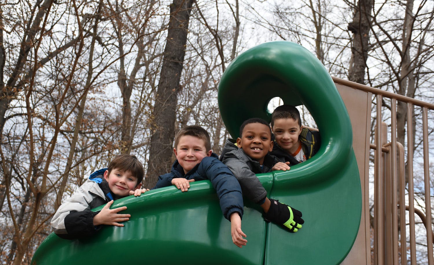 Four children in a green playground slide