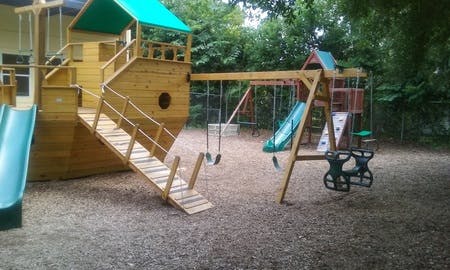 Playground with wooden ship structure, slide, and swings