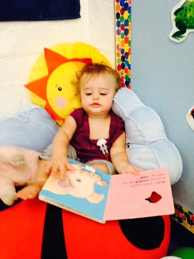 Child sitting with a book in a classroom