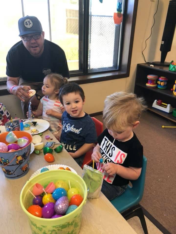 Person and three children at a table with buckets of plastic eggs