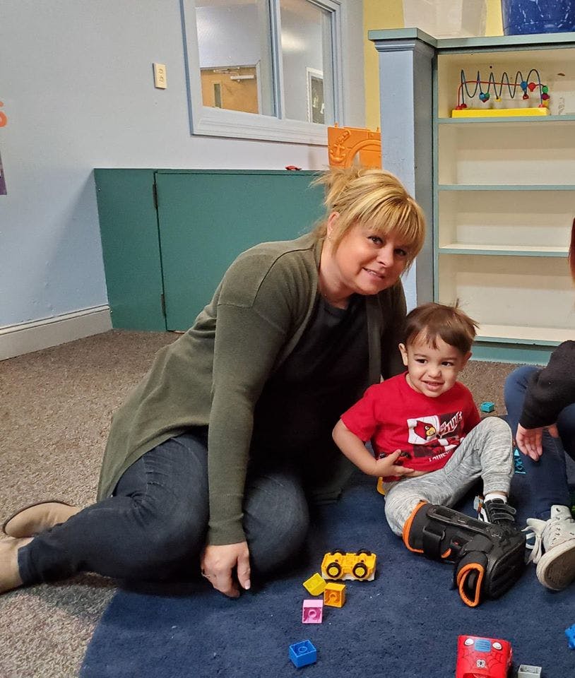 Person and child sitting on floor with toys