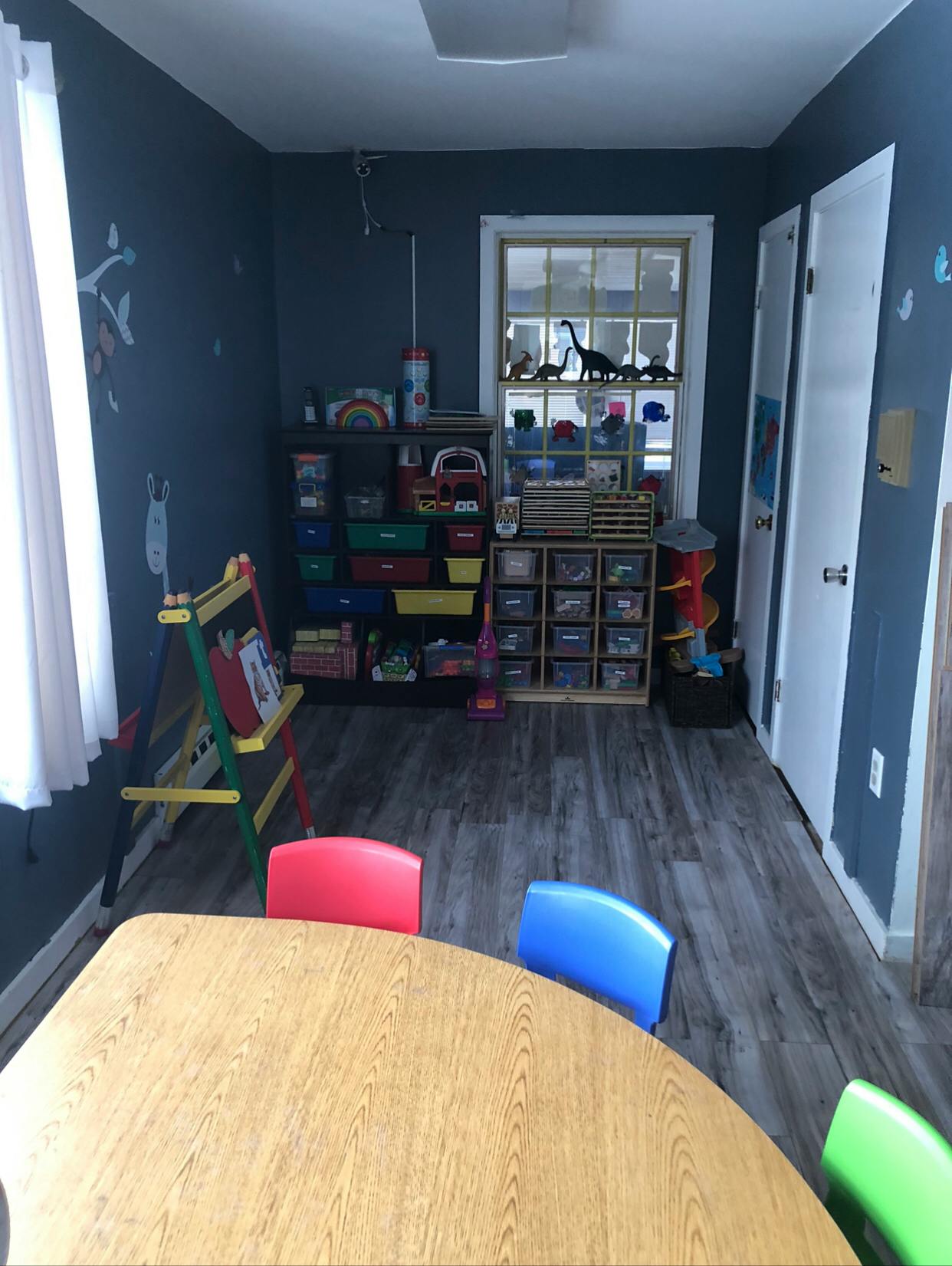 Classroom with small table and chairs, shelves with toys, and window