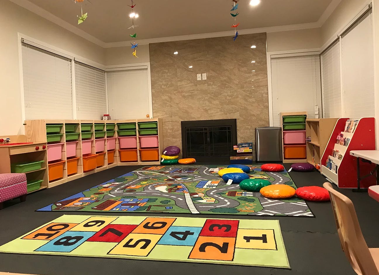 Playroom with colorful rugs, storage bins, and cushions