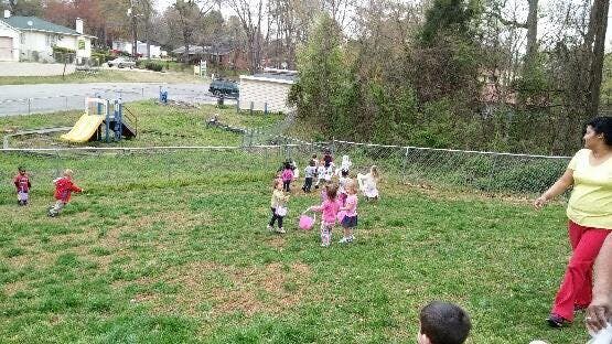 Children playing in a grassy yard with an adult nearby