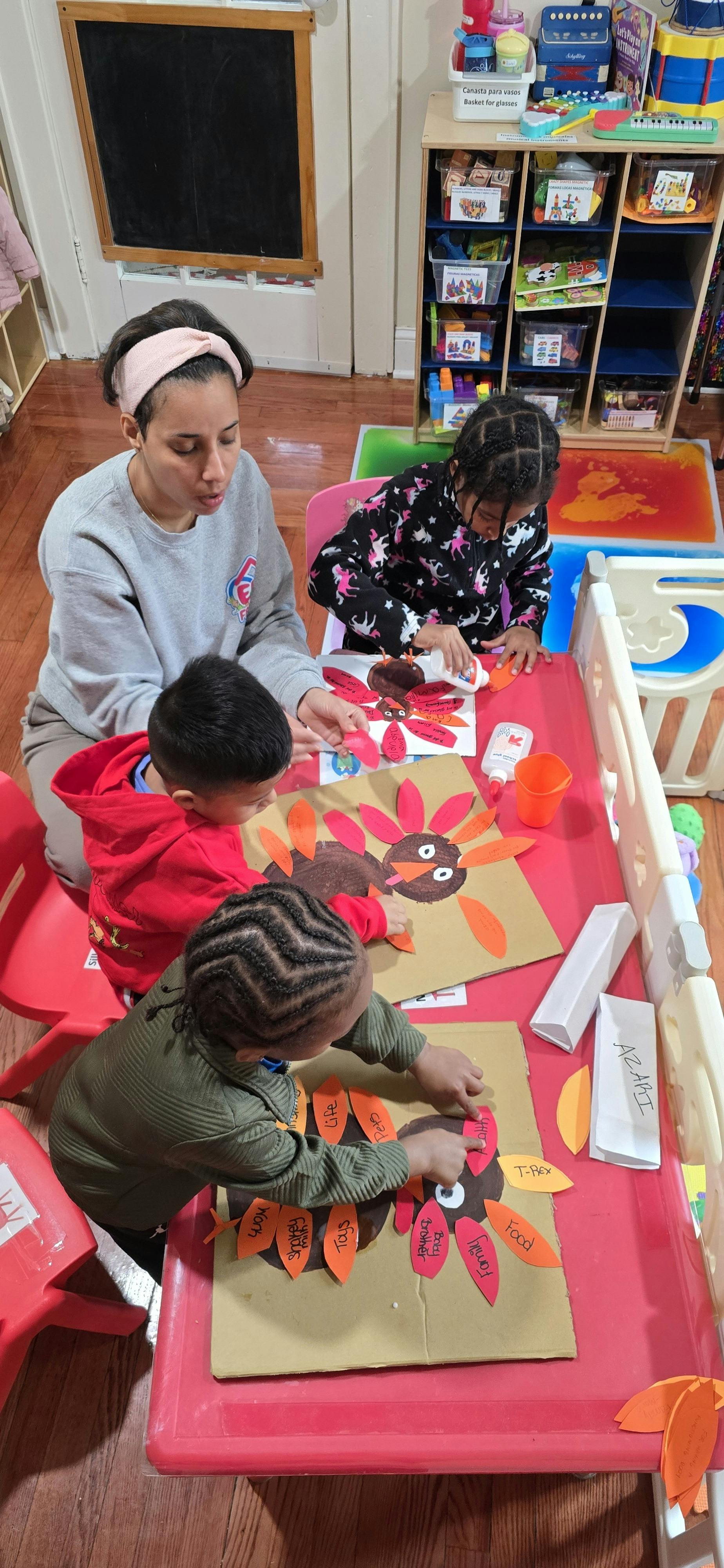 adult and three children making turkey crafts in a classroom